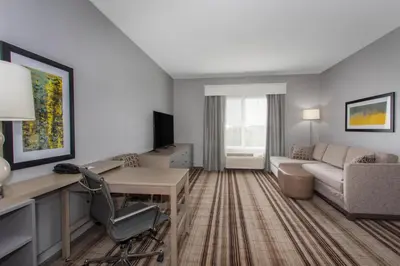 a living room with a couch and a desk in a room at Hawthorn Extended Stay by Wyndham Loveland in Johnstown