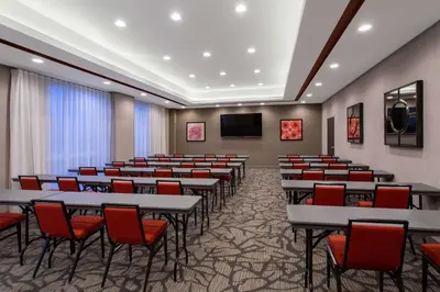 a conference room with tables and red chairs at Hawthorn Extended Stay by Wyndham Loveland in Johnstown