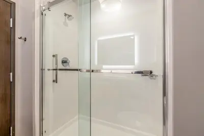 a bathroom with a shower with a glass door at Hawthorn Extended Stay by Wyndham Loveland in Johnstown
