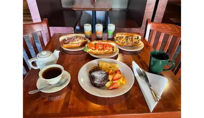a table with plates of food and a cup of coffee at Hilltop Inn Broomfield Denver in Broomfield