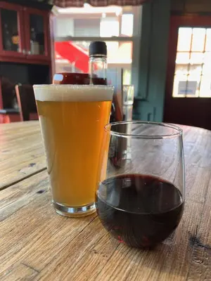 a glass of wine and a glass of beer on a wooden table at Hilltop Inn Broomfield Denver in Broomfield