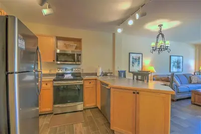 a kitchen with a stainless steel refrigerator and a living room at Cozy And Quaint 1 Bedroom Condo In The Heart Of River Run Village in Keystone