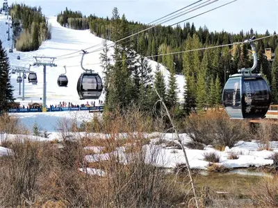 a ski lift with people riding on it in the snow at Cozy And Quaint 1 Bedroom Condo In The Heart Of River Run Village in Keystone