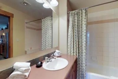 a bathroom with a sink and a mirror and a tub at 3 Bedroom Mountain View Condo In River Run Village Just 75 Yards From The Summit Express Gondola in Keystone
