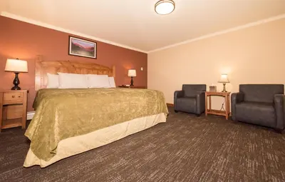 a hotel room with a bed and two chairs at The Maxwell Inn in Estes Park