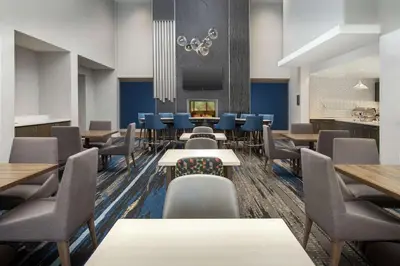a dining room with tables and chairs and blue chairs at Homewood Suites By Hilton Denver Airport Tower Road in Denver