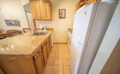 a kitchen with a white refrigerator and wooden cabinets at 2 Bedroom Colorado Mountain Vacation Rental In River Run Village With Hot Tub Access And Walking Distance To Ski in Keystone