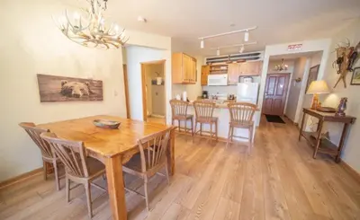 a dining room and kitchen with a wooden table and chairs at 2 Bedroom Colorado Mountain Vacation Rental In River Run Village With Hot Tub Access And Walking Distance To Ski in Keystone