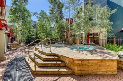 a patio with a hot tub and stairs in a yard at 1 Bedroom Mountain Condo In River Run Village With Beautiful Mountain Views And Walking Distance To Ski in Keystone