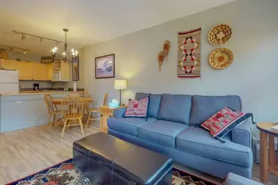 a living room with a blue couch and a kitchen at 1 Bedroom Mountain Condo In The Heart Of River Run Village Within Walking Distance To Ski in Keystone