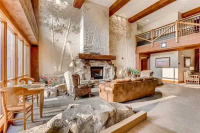 a living room with a stone fireplace and a couch at 2 Bedroom Colorado Vacation Rental Situated In River Run Village Steps From The Summit Express Gondola in Keystone