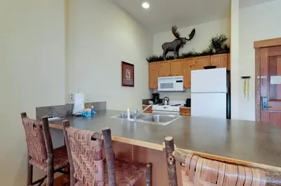 a kitchen with a counter with chairs and a refrigerator at 2 Bedroom Colorado Vacation Rental Situated In River Run Village Steps From The Summit Express Gondola in Keystone