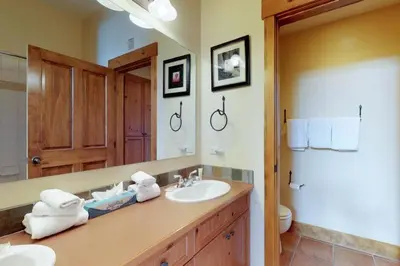 a bathroom with a sink and a toilet and a mirror at 2 Bedroom Colorado Vacation Rental Situated In River Run Village Steps From The Summit Express Gondola in Keystone