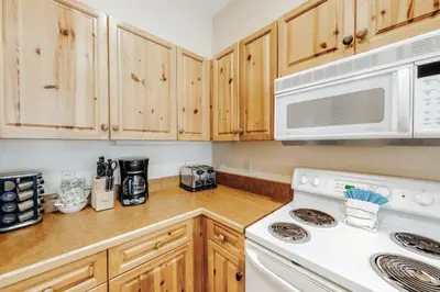 a kitchen with wooden cabinets and a white stove top oven at 1 Bedroom Colorado Vacation Rental In River Run Village Steps From The Summit Express Gondola in Keystone
