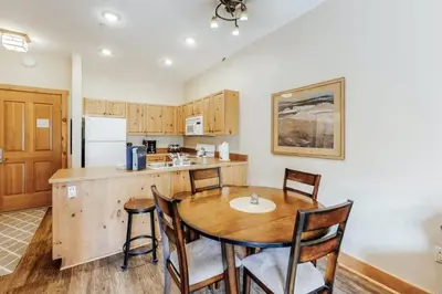 a kitchen with a wooden table and chairs in a kitchen at 1 Bedroom Colorado Vacation Rental In River Run Village Steps From The Summit Express Gondola in Keystone