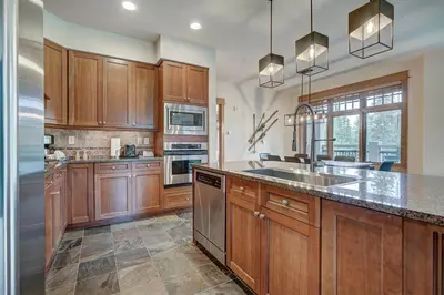 a kitchen with wooden cabinets and stainless steel appliances at Premier 3 Bedroom Ski In, Ski Out Lone Eagle Condo With The Best Access To Skiing In Keystone in Keystone