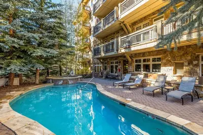 a swimming pool in front of a house with a building at Premier 2 Bedroom Ski In, Ski Out Lone Eagle Condo With The Best Access To Skiing In Keystone in Keystone