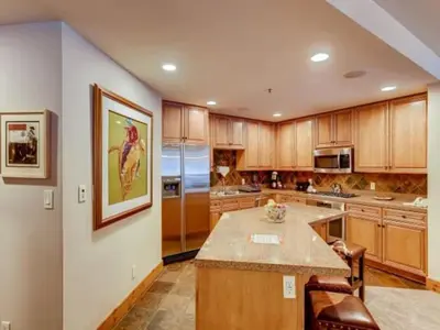 a large kitchen with wooden cabinets and a large island at Premier 2 Bedroom Ski In, Ski Out Vacation Rental At The Timbers With The Best Access To Skiing In Keystone in Keystone