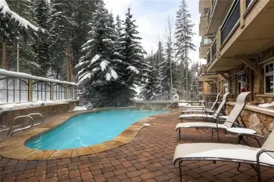 a swimming pool on a patio with chairs and trees at Premier 1 Bedroom Ski In, Ski Out Lone Eagle Condo With The Best Access To Skiing In Keystone in Keystone