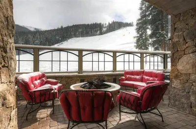 a balcony with red chairs and a table and a snowy mountain at Premier 1 Bedroom Ski In, Ski Out Lone Eagle Condo With The Best Access To Skiing In Keystone in Keystone