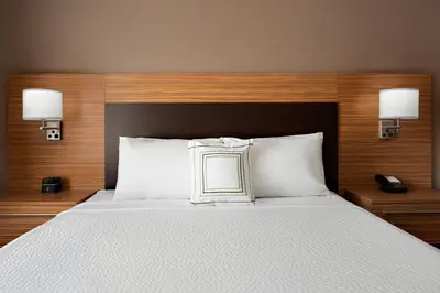 a bed with white pillows and a wooden headboard at TownePlace Suites by Marriott Loveland Fort Collins in Loveland