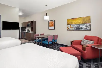 a hotel room with two beds and a dining room at TownePlace Suites by Marriott Loveland Fort Collins in Loveland