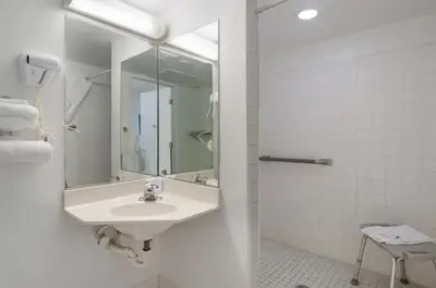 a white bathroom with a sink and a mirror at Rodeway Inn Greeley in Evans