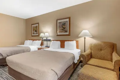 a hotel room with two beds and a chair at Quality Inn & Suites Wellington - Fort Collins in Wellington