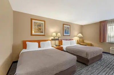a hotel room with two beds and a chair at Quality Inn & Suites Wellington - Fort Collins in Wellington