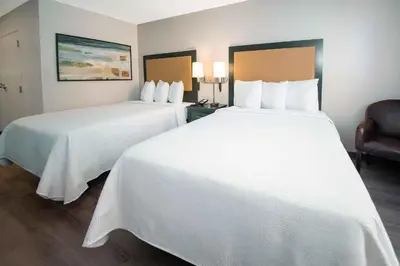 two beds in a hotel room with white sheets at Extended Stay America Suites - Denver - Westminster in Westminster