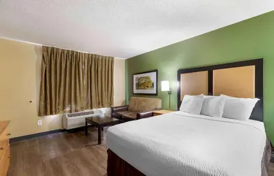 a hotel room with a large bed and a chair at Extended Stay America Select Suites - Denver - Cherry Creek in Denver