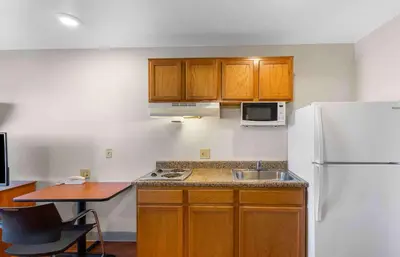 a kitchen with wooden cabinets and a white refrigerator at Extended Stay America Select Suites - Denver - Aurora in Aurora