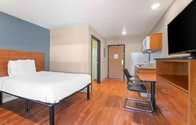 a bedroom with a bed and a desk and a kitchen at Extended Stay America Select Suites - Denver - Aurora in Aurora