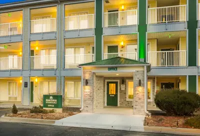 a large apartment building with a green door at HomeTowne Studios by Red Roof Denver - Glendale/ Cherry Creek in Denver