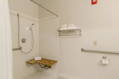 a bathroom with a shower with a wooden shelf at HomeTowne Studios by Red Roof Denver - Glendale/ Cherry Creek in Denver