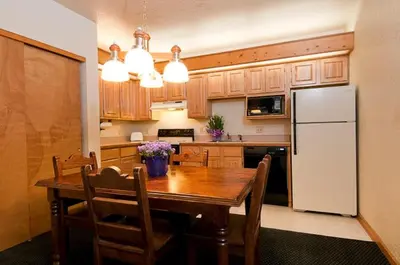 a kitchen with a wooden table and a white refrigerator at Wildwood Inn in Estes Park