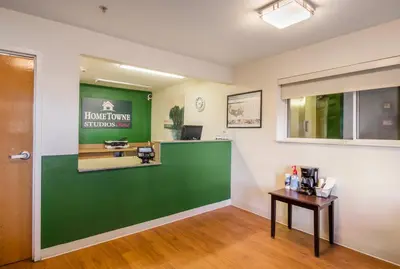 a waiting room at a hair salon with a green wall at HomeTowne Studios by Red Roof Denver - Airport/Aurora in Aurora