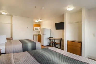 a hotel room with two beds and a table at HomeTowne Studios by Red Roof Denver - Airport/Aurora in Aurora