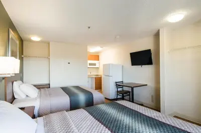 a hotel room with two beds and a small table at HomeTowne Studios by Red Roof Denver - Thornton in Thornton