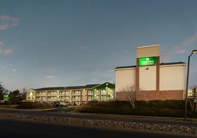 a hotel building with a green sign on it at HomeTowne Studios by Red Roof Denver - Thornton in Thornton