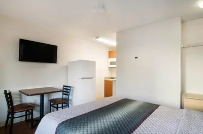 a bedroom with a bed and a table and a tv at HomeTowne Studios by Red Roof Denver - Thornton in Thornton