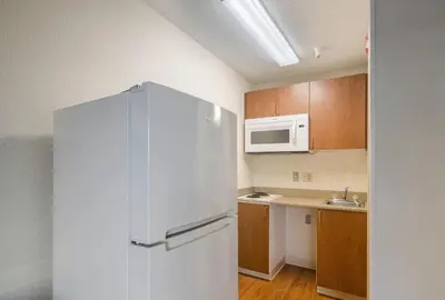 a kitchen with a refrigerator and a microwave at HomeTowne Studios by Red Roof Denver - Thornton in Thornton