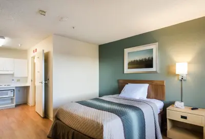 a small bedroom with a bed and a kitchen at HomeTowne Studios by Red Roof Denver - Thornton in Thornton