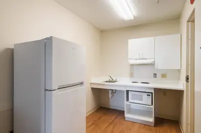 a kitchen with a refrigerator and a microwave at HomeTowne Studios by Red Roof Denver - Thornton in Thornton