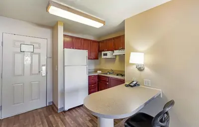 a kitchen with a white refrigerator and a table at Extended Stay America Suites - Denver - Aurora North in Aurora