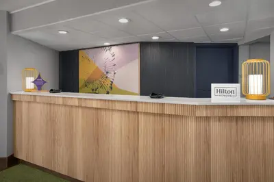 an office lobby with a reception counter with a sign at Spark by Hilton Denver East I 70 in Denver