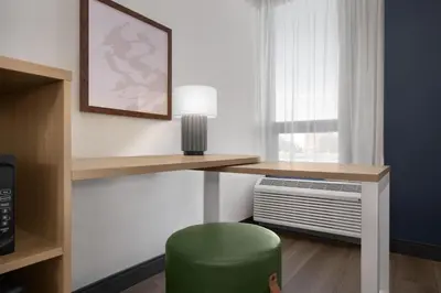 a room with a desk with a green stool and a window at Spark by Hilton Denver East I 70 in Denver