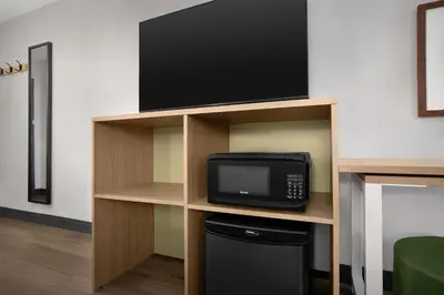a room with a tv on a shelf with a microwave at Spark by Hilton Denver East I 70 in Denver