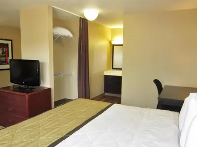 a hotel room with a bed and a desk and a television at Extended Stay America Select Suites - Denver - Tech Center - Central in Greenwood Village