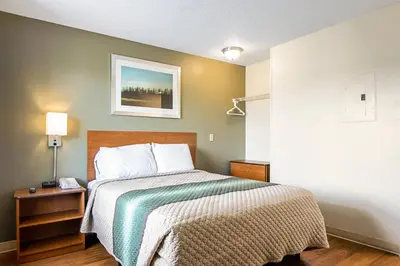 a bedroom with a bed and a picture on the wall at HomeTowne Studios by Red Roof Denver - Lakewood West in Lakewood